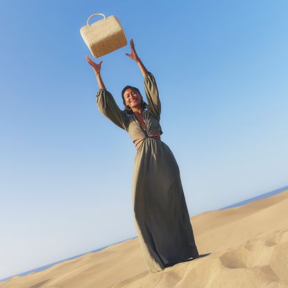 Woman in the desert wearing clothese from The Outnet and holding a bag above her head